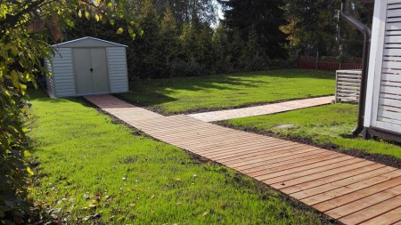 Itse rakennettu puinen terassikäytävä pihalla