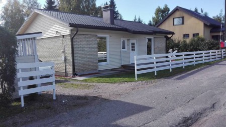 Valkoinen piha-aita ja kunnostettu pientalon julkisivu